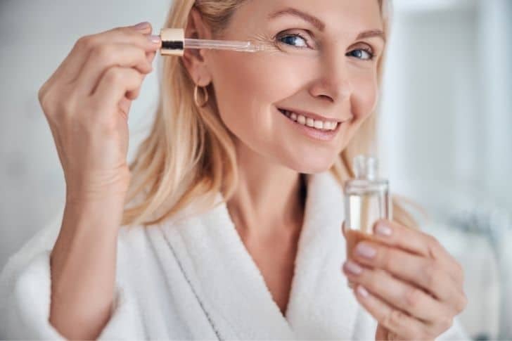 Mujer aplicándose aceite de jojoba para la cara.